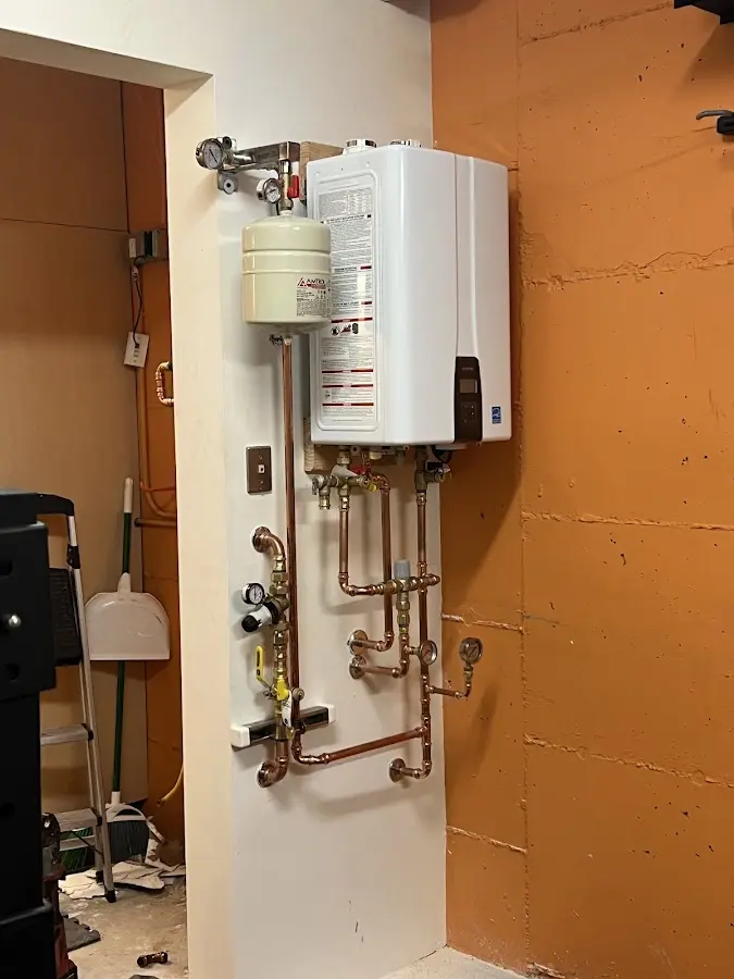 Plumbing technician inspecting water heater connections in Prien